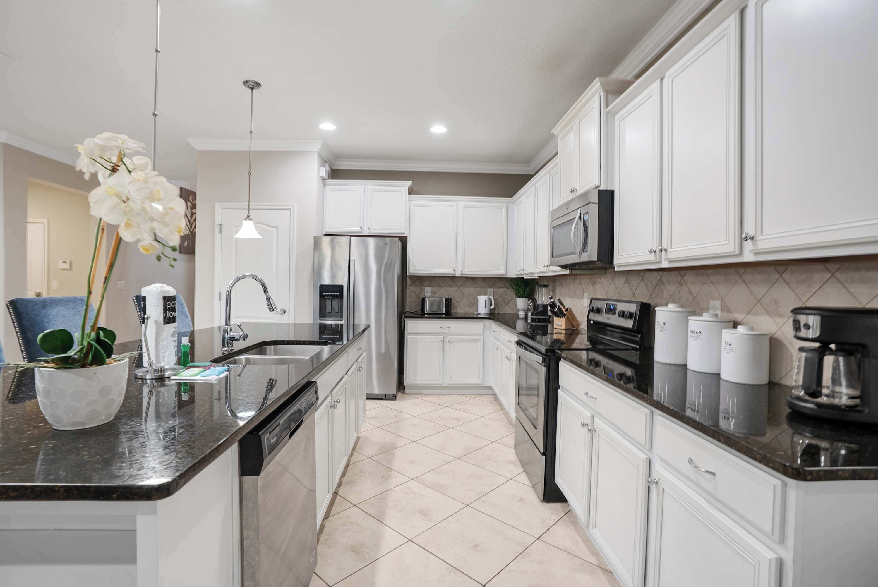 A modern kitchen with white cabinets, stainless steel appliances, and a granite countertop.