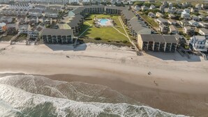 Ett hotell vid kusten med en pool i mitten, direkt tillgång till stranden och utsikt över havet.