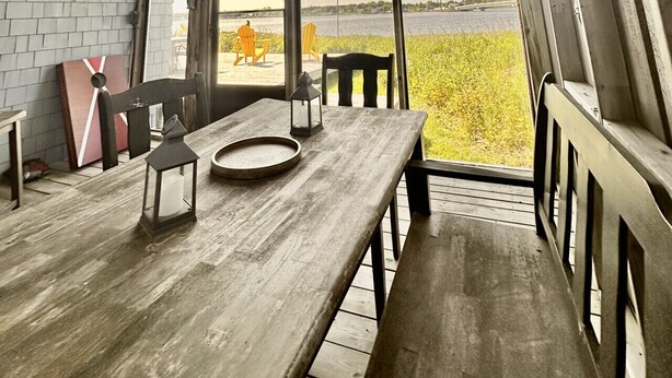 A wooden interior with a table, chairs, and a view of the outdoors. - Coastal Lines Retreat Ocean Views Sleeps 9 (Cocagne)