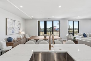 Eine moderne Küche mit Spüle aus Edelstahl, eine Essecke mit Holztisch und -stühlen sowie große Fenster mit Blick auf einen Vergnügungspark.