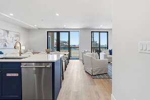 Eine moderne Küche mit eingebautem Geschirrspüler, ein Essbereich mit weißem Tisch und Stühlen sowie ein Balkon mit Blick auf einen Wasserpark.