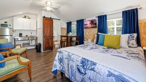 Ein Schlafzimmer mit Bett, Schreibtisch, Stuhl, einer Küchenzeile und einem Badezimmer.