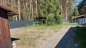 Kivipolku johtaa puiseen rakennukseen, jonka ympärillä on aidattu alue ja jonka yläpuolella on katettu rakenne.