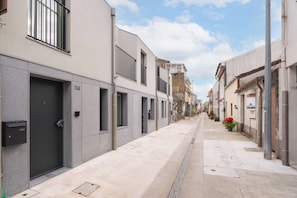 Una stretta via cittadina con edifici, cielo sereno e il numero civico 114 ben visibile.
