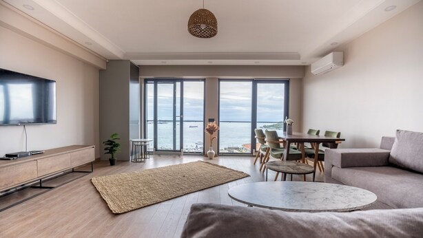 A modern living room with a flat-screen TV, a round coffee table, a sofa, and a dining area with chairs. - Bosphorus View 2BR Luxury Apartment - Parking & Elevator (İstanbul)