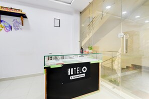 Ein Empfangsbereich mit der Beschriftung "HOTELO", einer Glastrennwand, einer Treppe im Hintergrund und einer Wand mit motivierenden Zitaten und einer Schmetterlingsillustration.