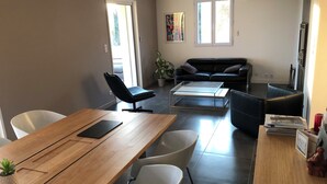 A modern living room with a wooden dining table, black leather sofas, and a glass coffee table. - Magnificent Bastide with swimming pool in the heart of nature (Puéchabon)