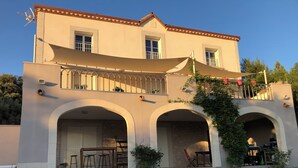 A two-story building with a balcony, arched doorways, and a covered outdoor seating area. - Magnificent Bastide with swimming pool in the heart of nature (Puéchabon)