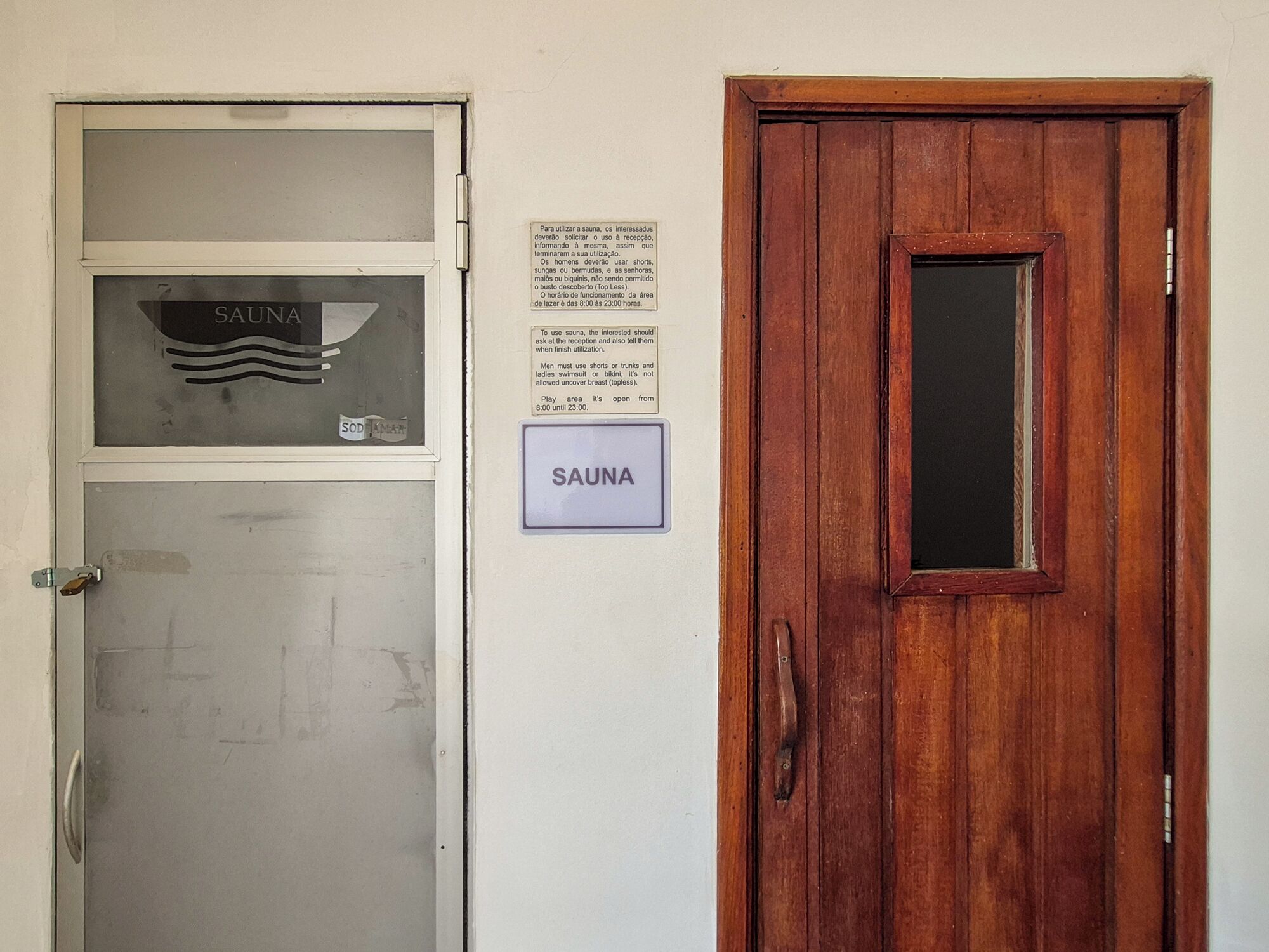 Puerta de sauna con un letrero, puerta de madera y un letrero adherido a la pared con instrucciones.