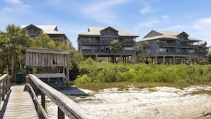 Ein Hotel direkt am Strand mit mehrstöckigen Gebäuden, einer Holzpromenade und einem Sandstrand.