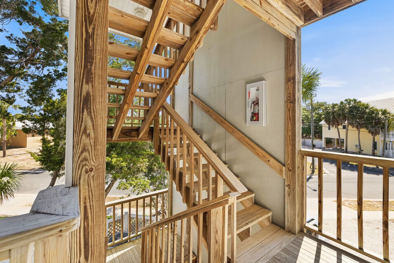A wooden staircase leading to a balcony with a fire extinguisher mounted on the wall.