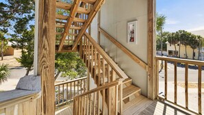 A wooden staircase leading to a balcony with a fire extinguisher mounted on the wall.
