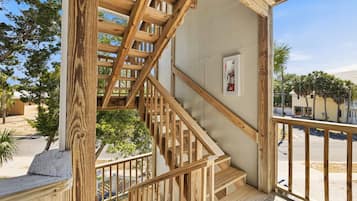 A wooden staircase leading to a balcony with a fire extinguisher mounted on the wall.