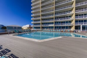 Ein mehrstöckiges Hotel mit Poolbereich, inklusive Pool, Liegestühlen und einer Sonnenterrasse.