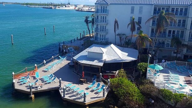 Et hotel ved vandet med poolområde, udendørs siddepladser og udsigt over havet.