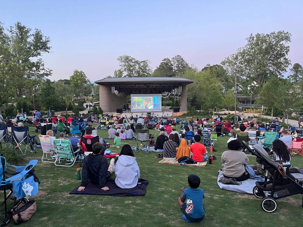 An outdoor event with a stage and audience on grass.