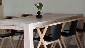 Une table à manger ornée d’un vase de fleurs, entourée de chaises.
