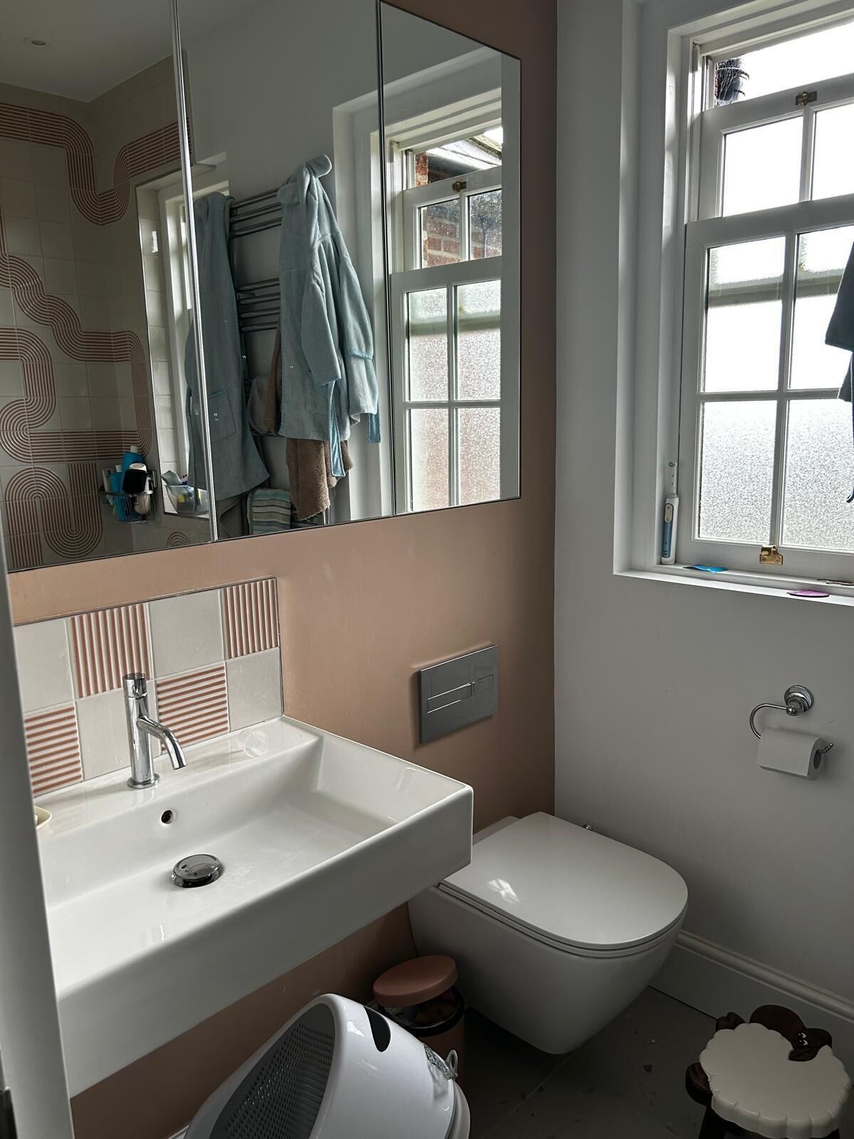 Un bagno con un lavandino bianco, un water, uno specchio e una finestra.