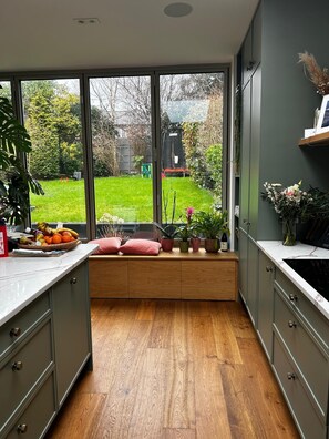 A kitchen with a built-in bench, large windows, and a view of a garden. - Fabulous 4-bedroom family home in tranquil Dublin neighborhood 10 mins from town (Dublin)