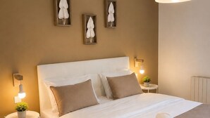 A neatly made bed with pillows, a bedside table with a plant, and wall-mounted artwork. - T3 6 pers - Sea view - Beach 1 min away - Terrace - WiFi fibre 1Gb - PortAventura (Salou)