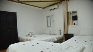 Quarto com duas camas, guarda-roupa, janela e ar condicionado.