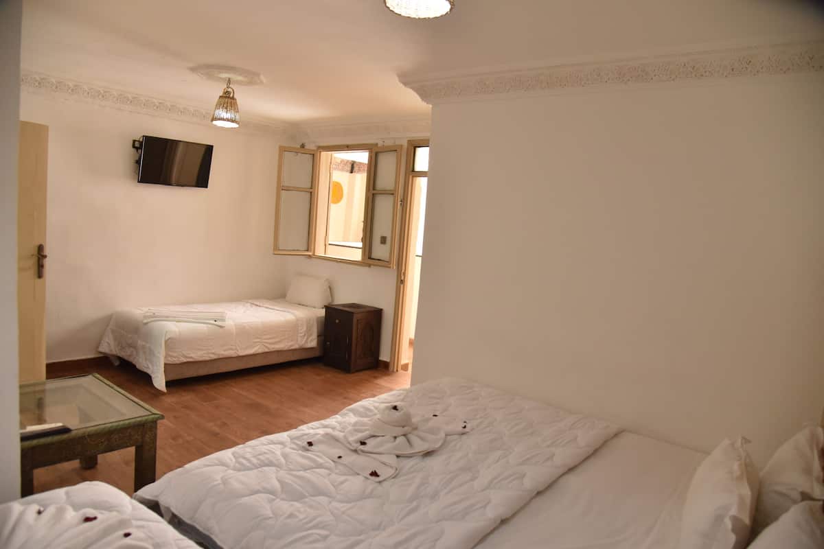 Ein Zimmer mit zwei Betten, einem Fernseher, einem kleinen Tisch und einem Fenster mit Blick.
