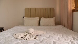 Cama bem arrumada com cabeceira, travesseiros e toalhas organizadas.
