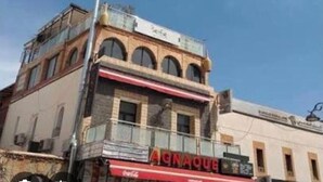 Um edifício com vários andares, com um restaurante chamado 'AGNAQUE' no andar térreo.