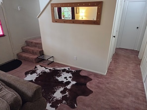 A staircase with a mirror, a cowhide rug, and a door.
