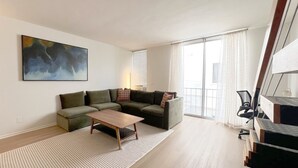 Una sala de estar moderna con un sofá seccional, una mesa de centro y un cuadro grande en la pared.