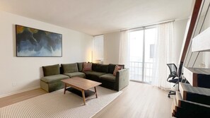 Ein modernes Wohnzimmer mit einem Ecksofa, einem Couchtisch und einem großen Gemälde an der Wand.