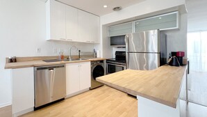 Una cocina moderna con electrodomésticos de acero inoxidable, encimeras de madera y armarios blancos.