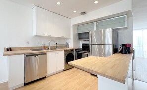 Eine moderne Küche mit Edelstahlgeräten, Holz Arbeitsplatten und weißen Schränken.