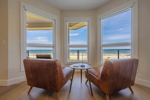 Ein Zimmer mit Meerblick, zwei Ledersessel, ein kleiner Tisch und ein Fenster zum Ozean.
