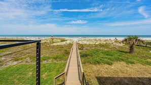 Une promenade en bois menant à une plage, avec un ciel dégagé.