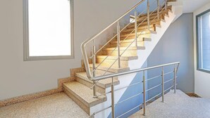 A staircase with metal railings, a window, and a carpeted floor. - Deluxe Sector 49 Sohna Road (Gurugram)