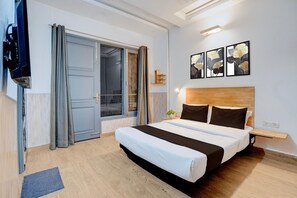 Un dormitorio con cama, televisor, puerta corredera y obras de arte en la pared.