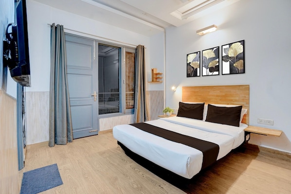 Un dormitorio con cama, televisor, puerta corredera y obras de arte en la pared.