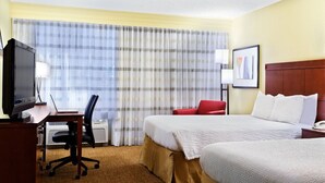 A hotel room with a bed, a desk with a computer, a television, and a red chair. - Relaxing Houston Suite with 2 Double Beds, Ideal for Families or Groups, 4 Units (Houston)