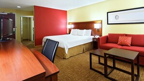 A hotel room with a bed, a red sofa, a wooden desk, and a television. - Relaxing Houston Stay with King Bed, Sofabed & Prime Location (Houston)
