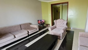 A living room with a sofa set, a coffee table, a television, and a chair.