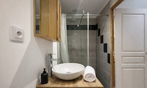 A bathroom with a white sink, a wooden countertop, a towel, a shower with a glass door, and a wooden cabinet above the sink. - La Dodane - Charming detached house - 4 pers - St Leu : 2 min des quais (Amiens)