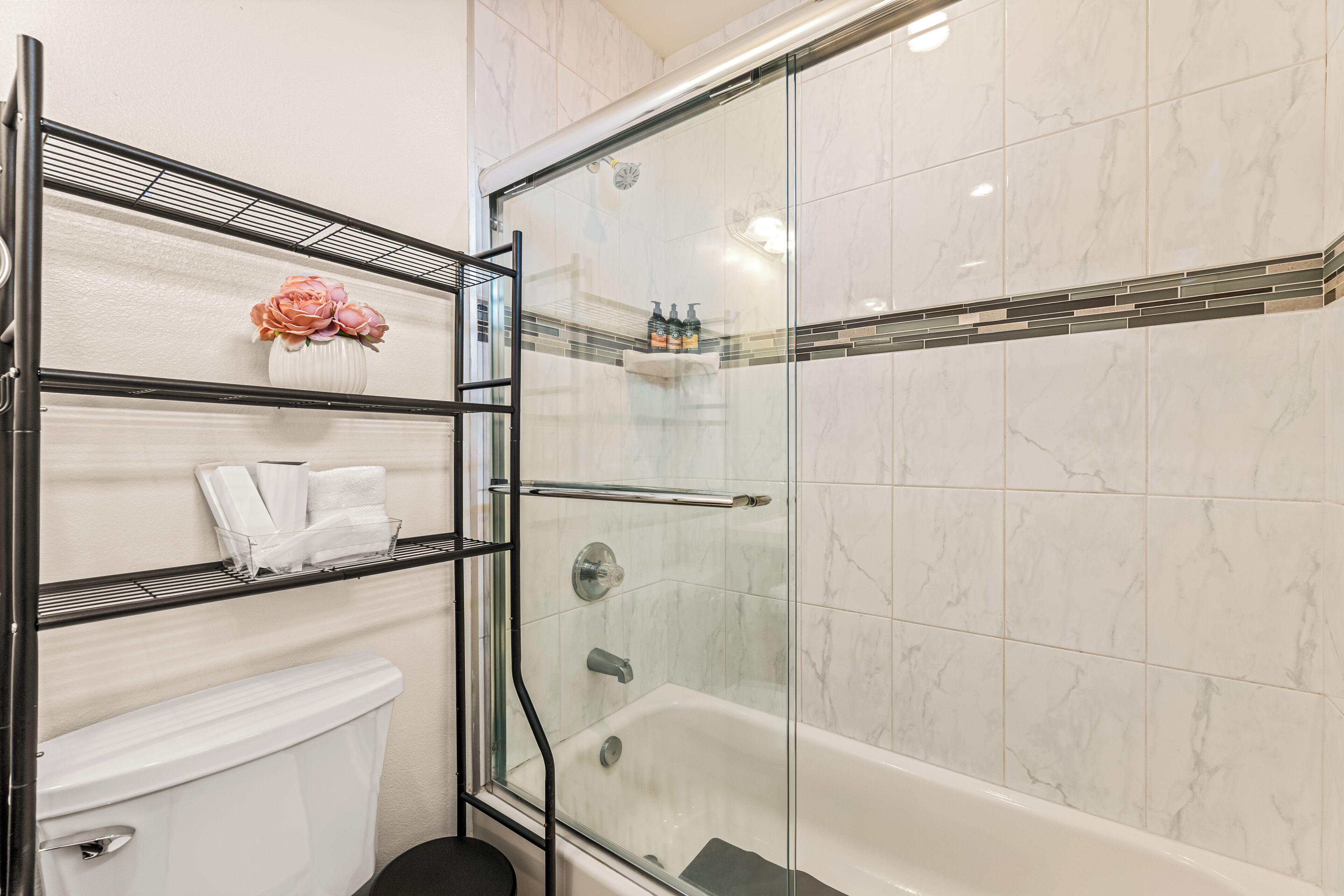 Een badkamer met een douchecabine, een toilet en een plank met toiletartikelen.
