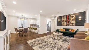 A modern living room with a dining area, a kitchen, and a large wall mural.