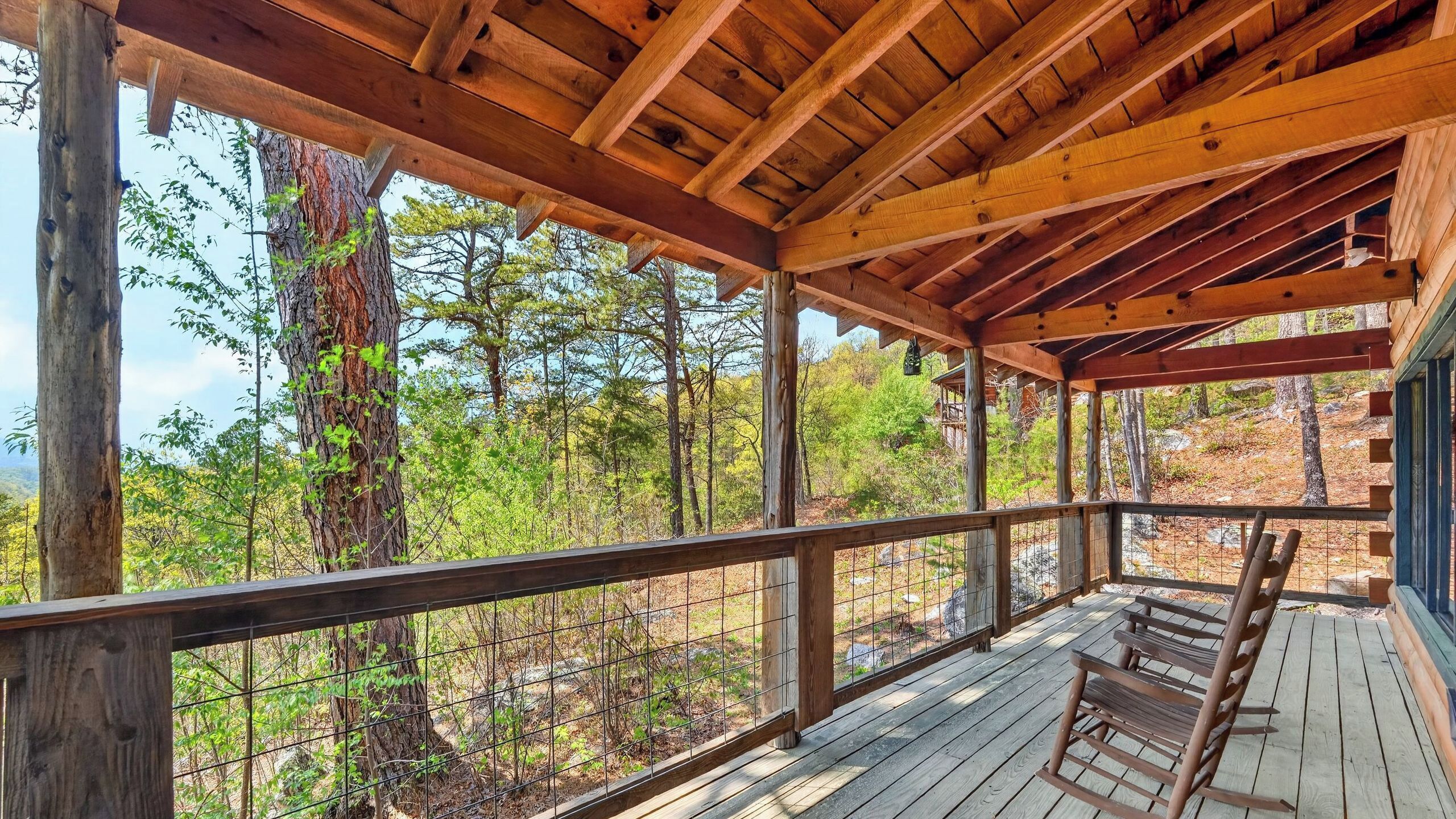 A wooden deck with a railing, overlooking a forested area.