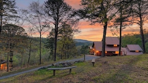 A cabin with a metal roof, surrounded by trees and a gravel path. - Sleeps 42, 7 Cabins Private Hot Tubs + Shared Fire Pit + Mountain Views + Covered Decks 7 Min to Townsend (Townsend)