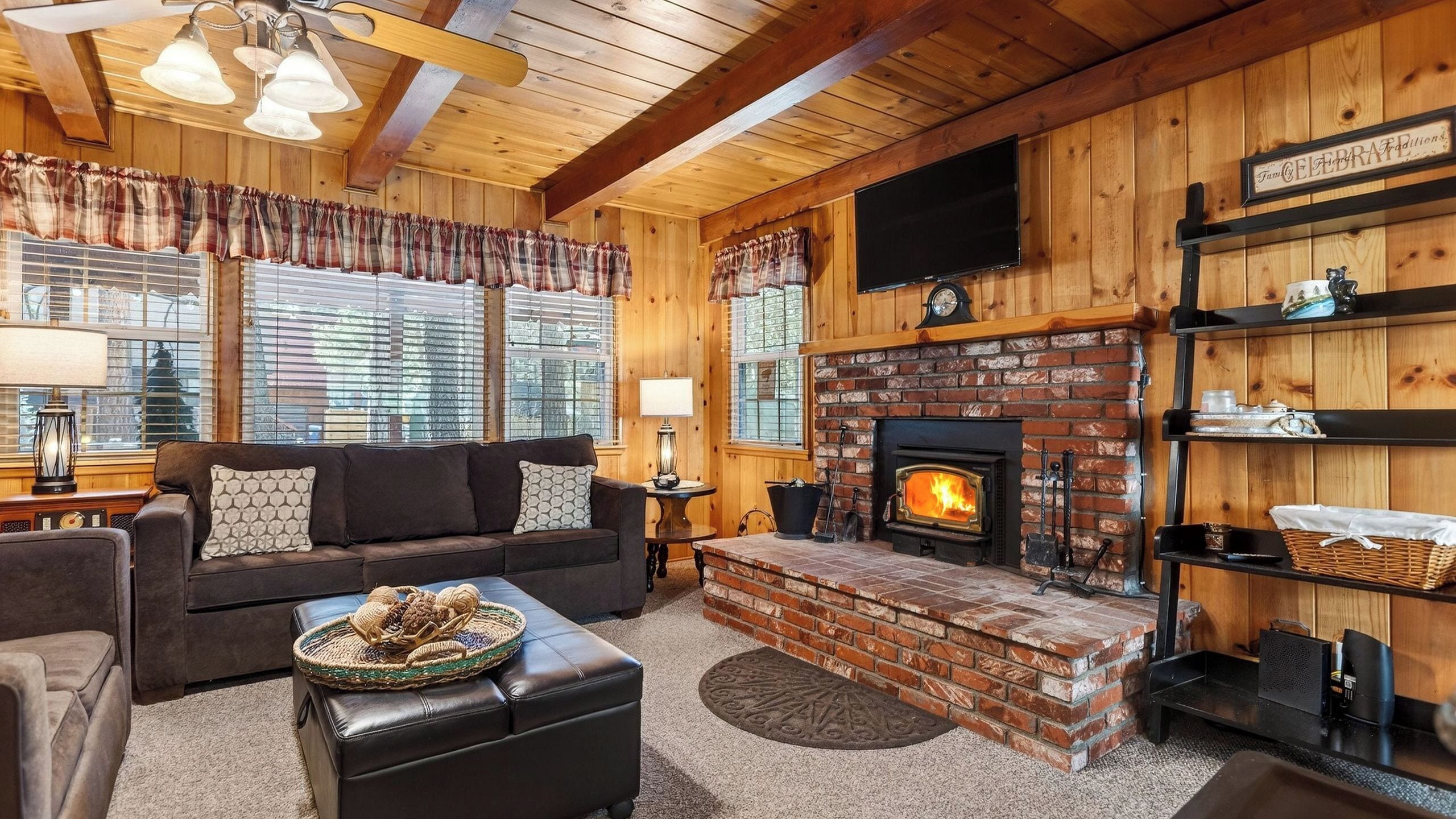 A cozy living room with a fireplace, wooden walls, a sofa, and a television.