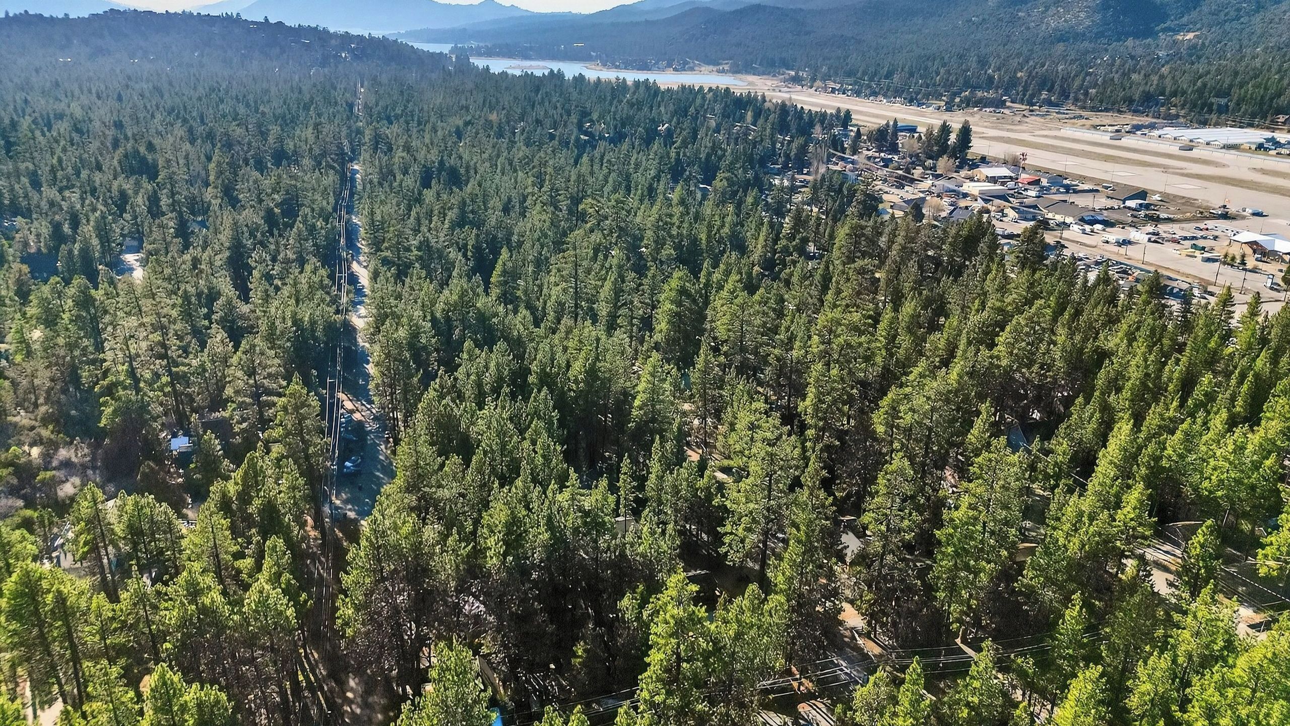 Metsäinen alue, jossa näkyy kauempana tie ja rakennuksia.