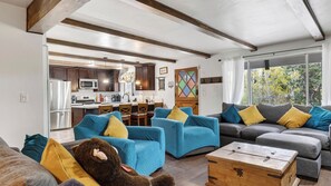 Ein modernes Wohnzimmer mit einer Couch, Sesseln, einer Bär-Dekoration und einer Holzkiste.