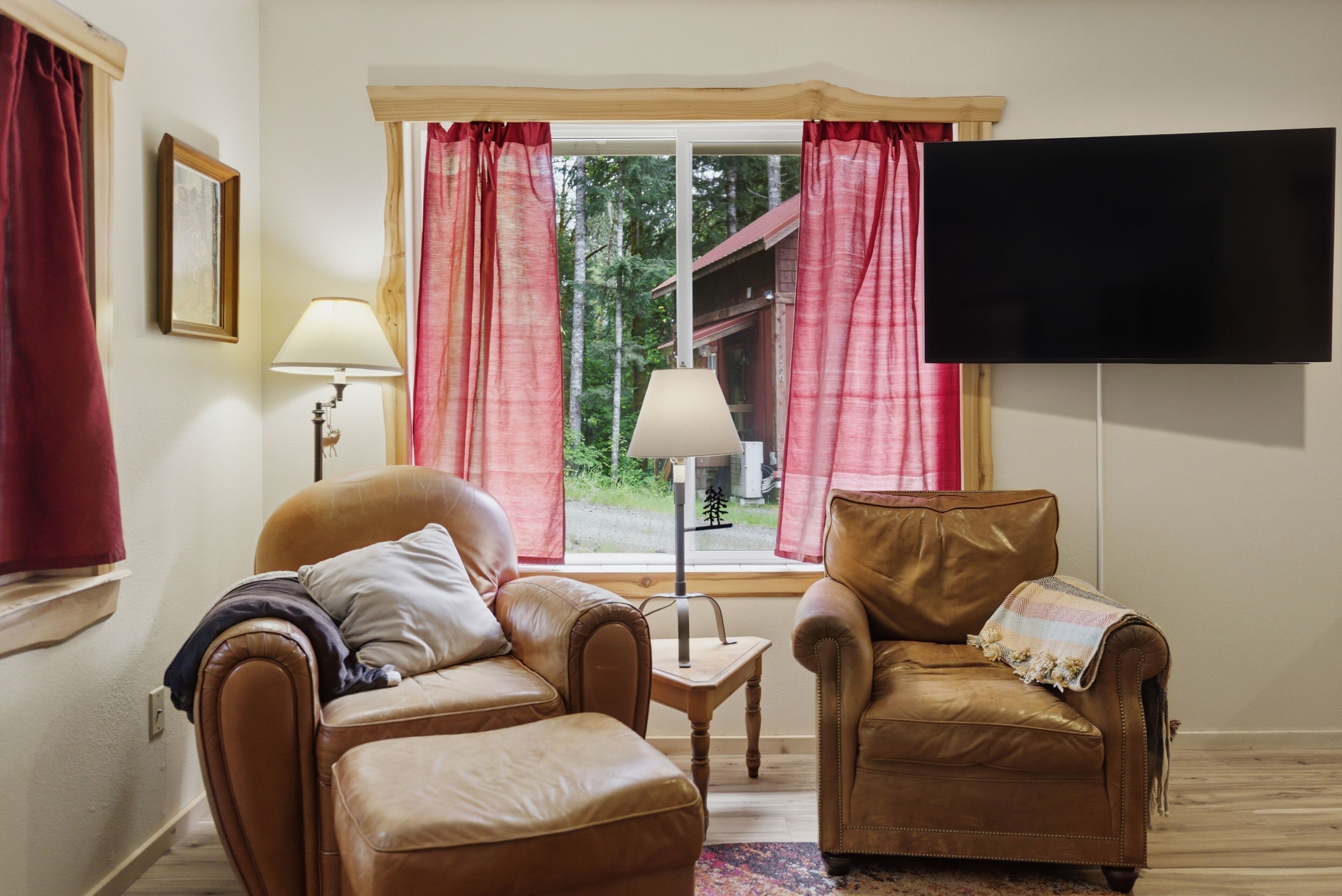 A living room with two leather sofas, a TV, and a window with curtains.